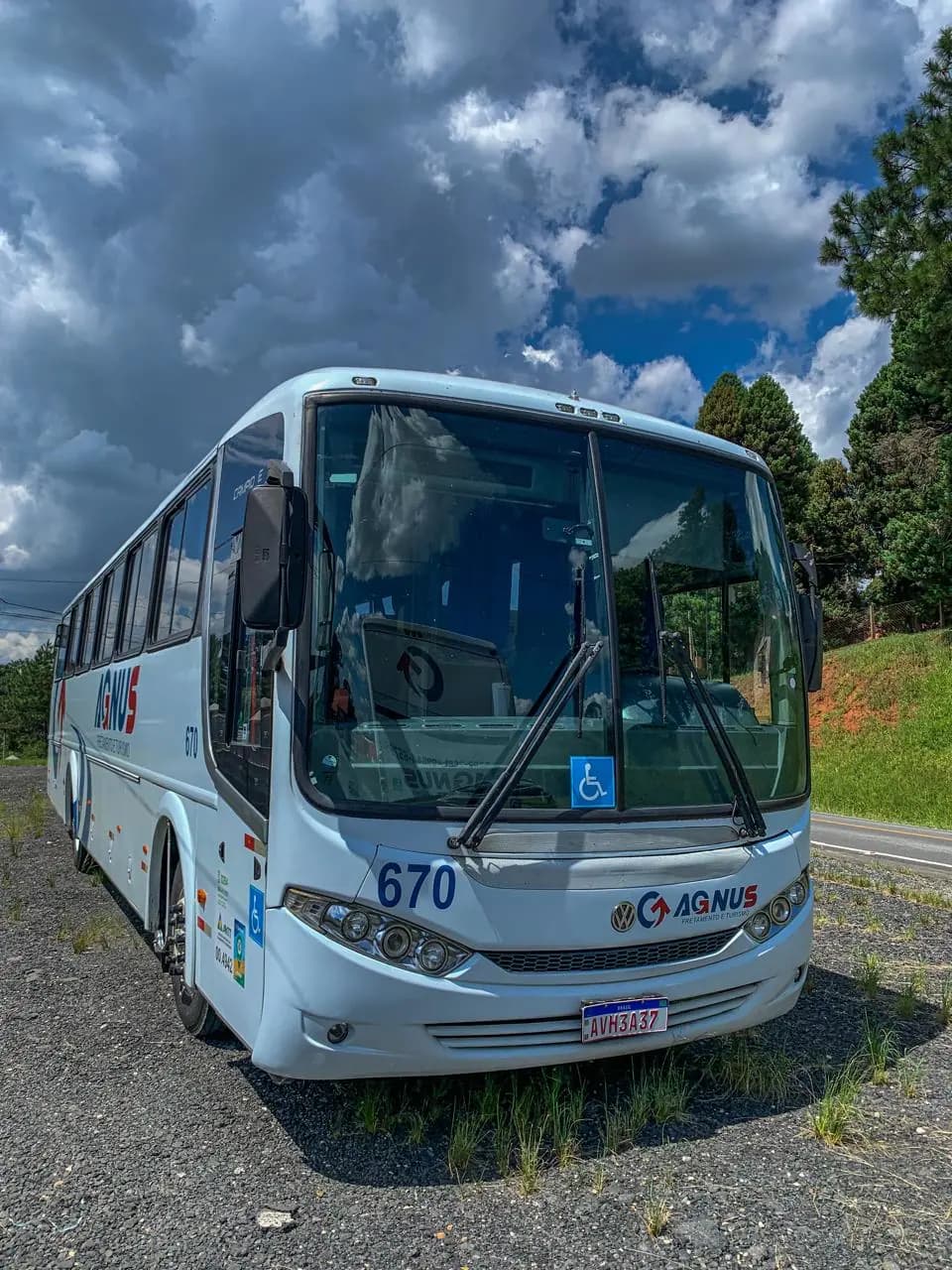 Ônibus da Agnus visto de frente, com a identidade azul e vermelha, junto a uma estrada.
