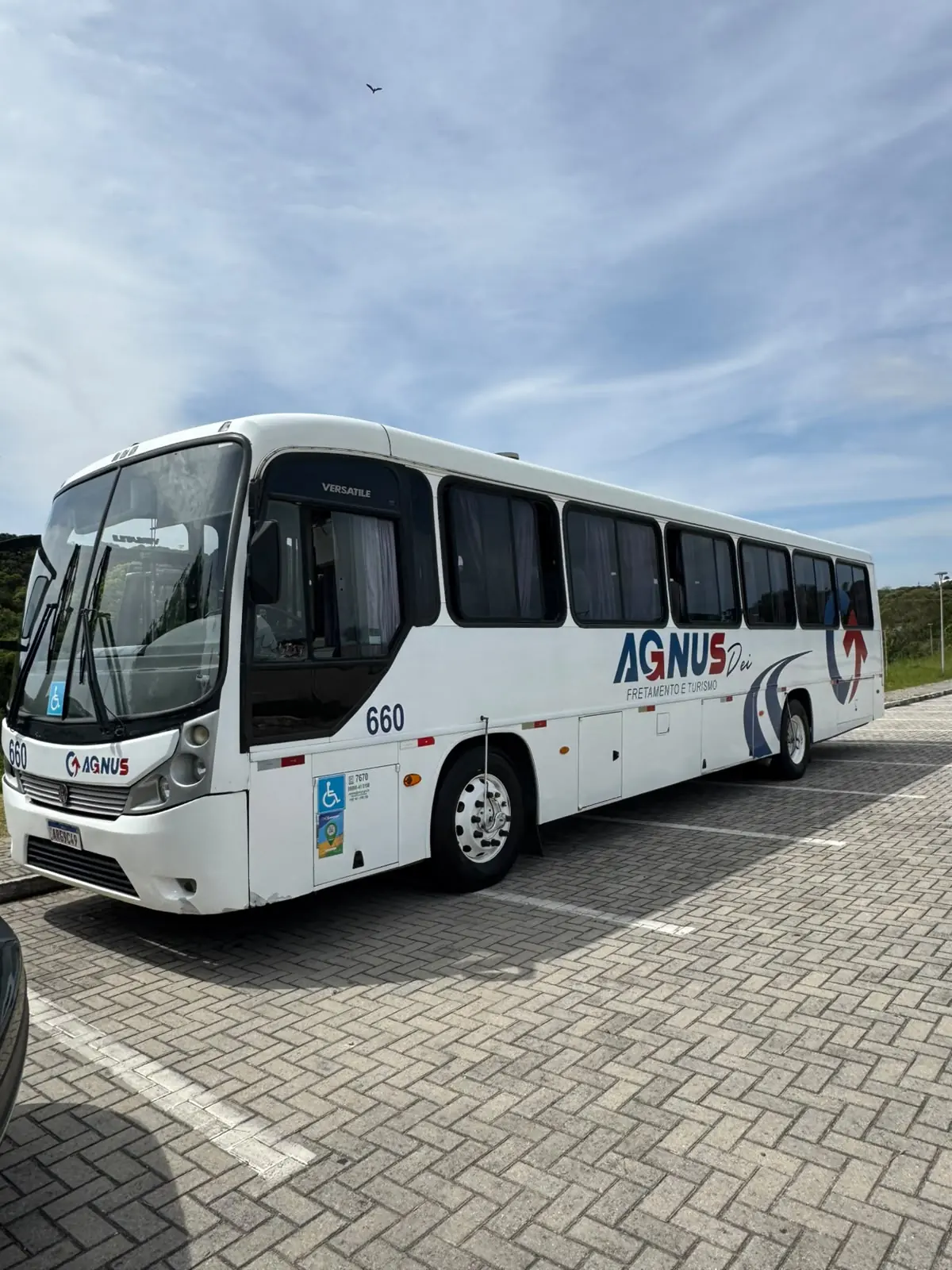 Frente e lateral de um ônibus da Agnus estacionado em uma área pavimentada.